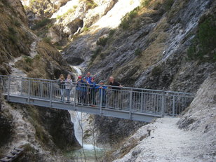 Kinder stehen fürs Gruppenfoto auf einer Eisenbrücke über einem Bergbach