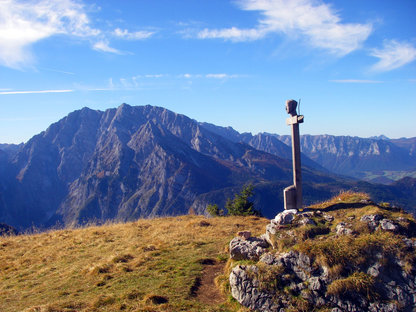 Goldene Gipfelwiese mit Holzkreuz und Berg im Hintergrund