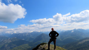 Mann am Gipfel mit Bergpanorama