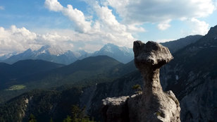 Bizarrer pilzförmiger Felsen vor wilder Bergkulisse