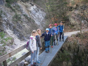 Gruppe mit Kindern auf einer Brücke in einem Wildbachtal 