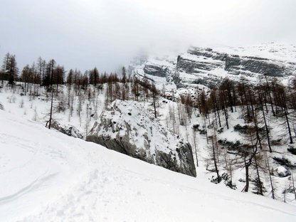 Großer, dachförmiger Felsblock in winterlicher Gebirgslandschaft