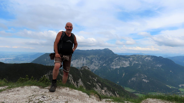 Bergsteiger am Gipfel mit Gebirge im Hintergrund 