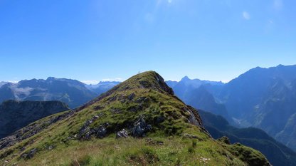 Grüner Gipfelgrat vor imposanter Bergkulisse