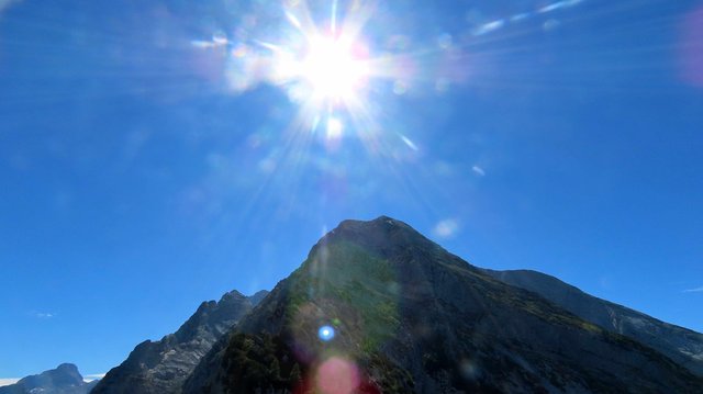 Die Sonne leuchtet über einem markanten Berg