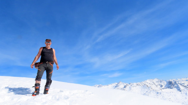 Skibergsteiger auf hohen Gipfel unter blauem Himmel mit Schleierwolken