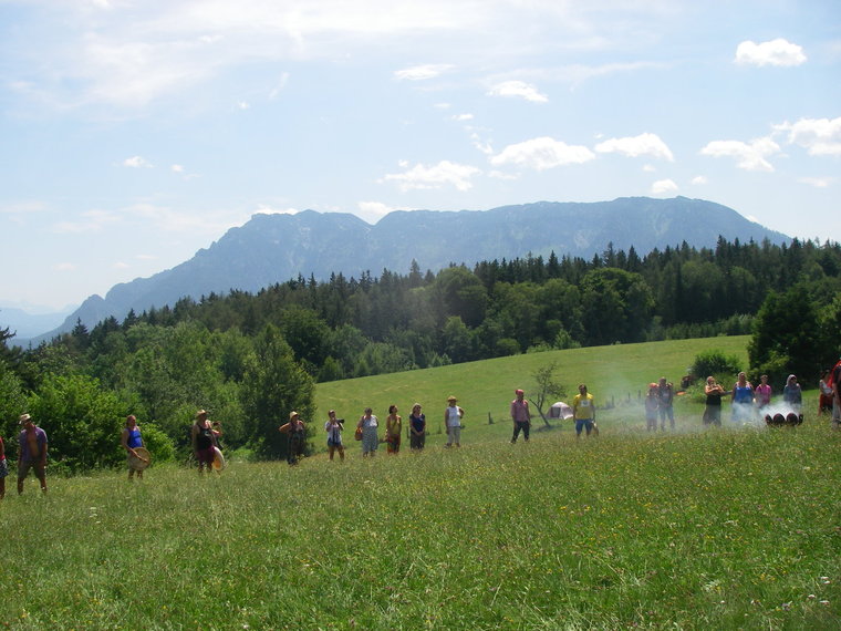 Mehrere Leute auf einer grünen Wiese und im Hintergrund ein Berg