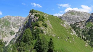 Grüner Wiesenberg in einem kargen Karstgebirge