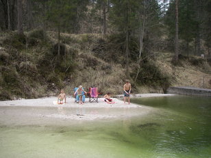 Kinder auf einer Kiesbank an einem kleinen Stausee 