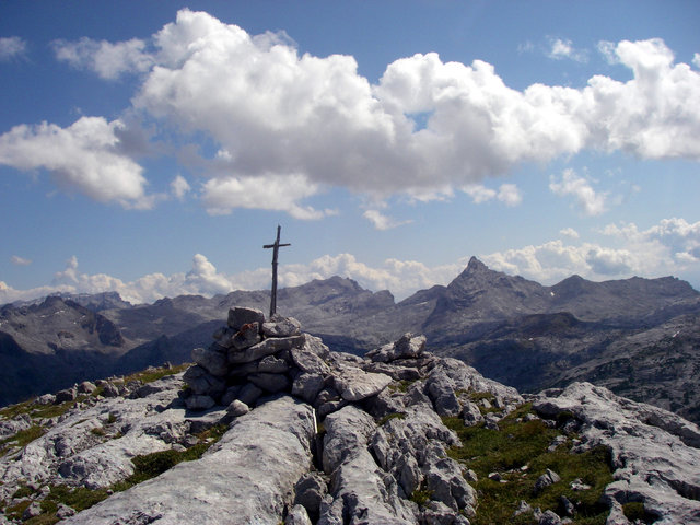 Auf einem Berggipfel mit einsamen Kreuz und Blick über ein weites Karstplateeu