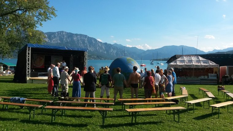 Viele Leute vor einer Bühne an einem großen See