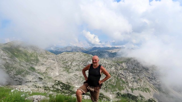 Gut gebräunter Bergsteiger mit T-Shirt und kurzer Hose in wilder Karstlandschaft