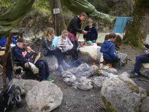 Kinder und Erwachsene beschäftigen sich individuell rund um die Feuerstelle 