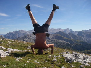 Mann macht Kopfstand in wilder Berglandschaft