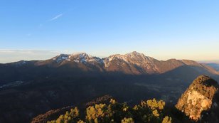 Letztes Abendlicht auf zwei Bergen, davor eine angeleuchtete Felswand