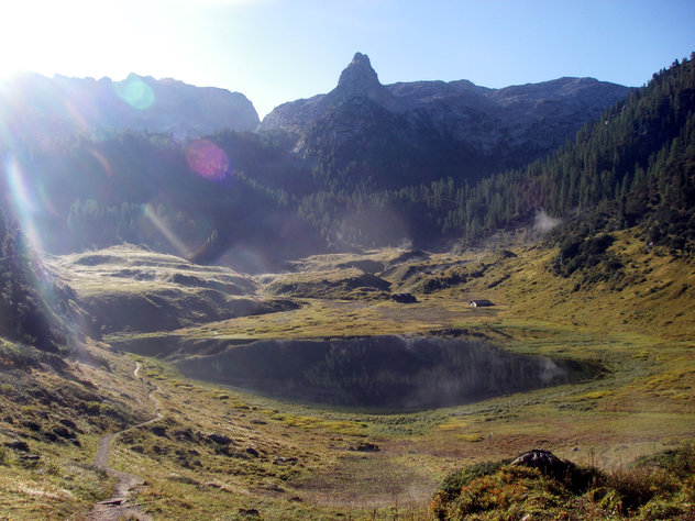 Morgensonne an einem Bergsee mit spitzen Berg im Hintergrund