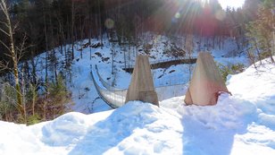 Massive Hängebrücke in einem winterlichen Bergtal 