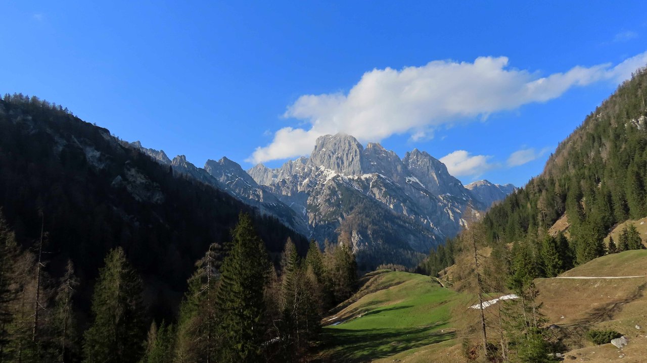 Felsberg mit Wolke über einem grünen, frühlingshaften Bergtal