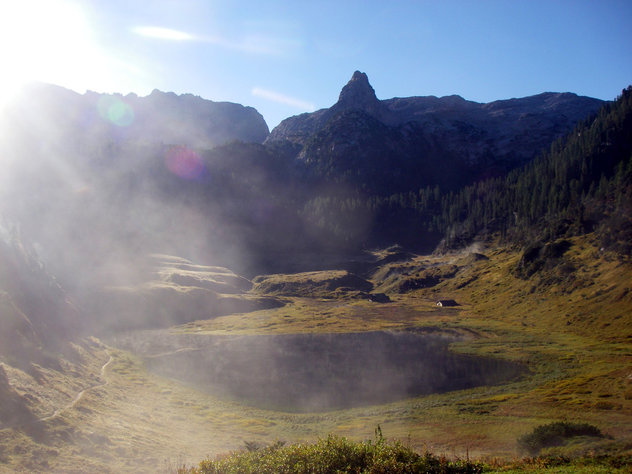 Nebelschwaden über einem kleinen Bergsee, im Hintergrund ein spitzer Gipfel